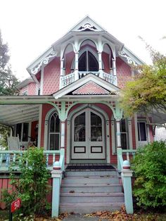 a pink and white victorian style house with an arched window, front door and porch