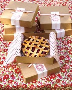 four boxes with pies in them sitting on a floral tablecloth covered table cloth