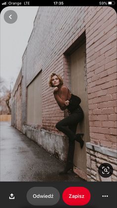 a woman leaning up against a brick wall