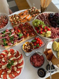 a table topped with lots of different types of plates and bowls filled with meats