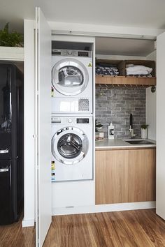 a washer and dryer in a small room with wood flooring on the walls