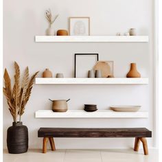 two white shelves with vases and bowls on them