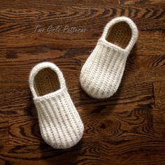 two crocheted white slippers sitting on top of a wooden floor next to each other