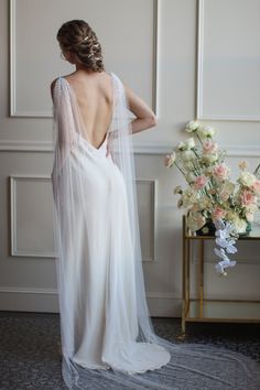 the back of a woman's wedding dress, with flowers and a vase in the background