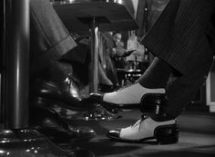 black and white photograph of man's feet wearing dress shoes