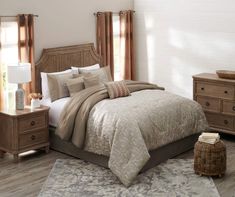 a bedroom with a bed, dressers and windows in the background on a wooden floor