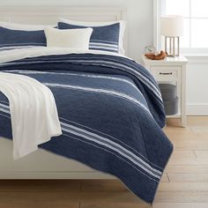 a bed with blue and white bedspread, pillows and blankets on top of it