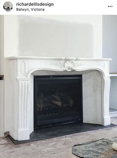 a white fireplace with a black mantle in the middle