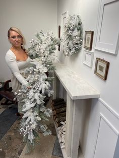 a woman standing next to a table holding a white christmas tree