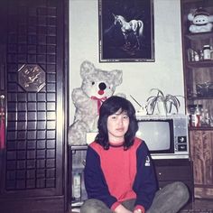 a woman sitting on the floor in front of a teddy bear