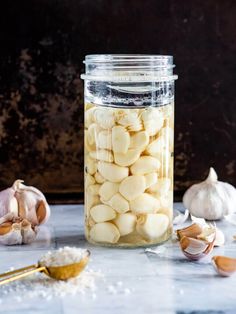 a glass jar filled with white chocolate covered marshmallows next to garlic cloves