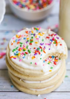 a stack of cookies with frosting and sprinkles next to a glass of milk