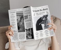 a woman sitting on a couch holding up a newspaper to her face with both hands