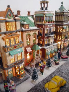 a toy town with cars and people on the street in front of buildings that are decorated for christmas