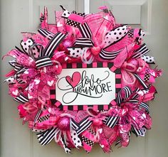 a pink and black valentine's day wreath with the word love you more on it