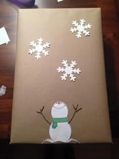 a cardboard box with snowflakes on it sitting on top of a wooden table