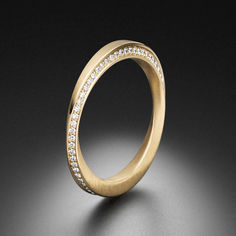 a yellow gold wedding ring with white diamonds on the inside and outside, against a black background