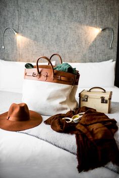 a bag, hat and purse sitting on top of a bed next to each other