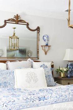 a bed with blue and white comforter in front of a mirror on the wall