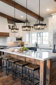 a kitchen island with stools and lights hanging from the ceiling