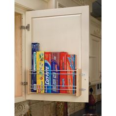 the kitchen cabinet door is open and has several cans on it, as well as a pull out spice rack