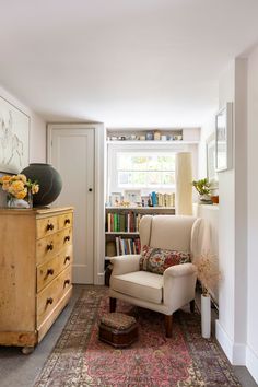 a living room filled with furniture and a book shelf on top of a carpeted floor