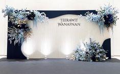 there is a backdrop with blue flowers and greenery on the front, along with white walls