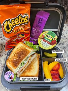 a lunch box with sandwiches, fruit and snacks