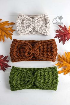 three crocheted headbands with bows and leaves in the background on a white surface