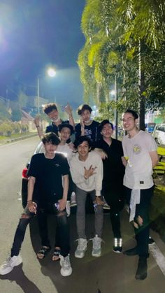 a group of young men standing next to each other on the side of a road