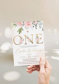 a person holding up a card with the word one on it and flowers in gold foil