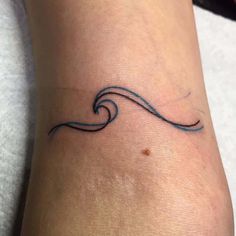 a small wave tattoo on the ankle is shown in black ink, and it appears to be an ocean wave