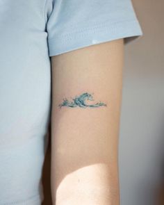 a person with a small wave tattoo on their arm