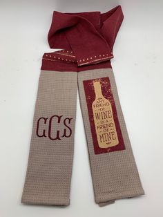 two wine bottle bags with the words gcs printed on them, one has a red scarf around it