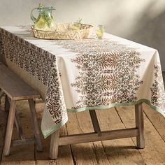 a table with a white and brown table cloth on top of it next to a wooden bench