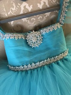 Your strong-spirited ice queen will twirl her heart out in this Elsa-inspired dress! This dress is essentially our ballerina flutter sleeve dress in luxurious light aqua tulle with the addition of beautiful silver trims and a sparkling rhinestone snowflake brooch to finish it off. ** Upon checkout, if you would like a perfect fit please include your child's chest size and length from belly button to desired hem. If you have any questions, please email us at bespoke@maraissky.com. CURRENT PROCESS Elegant Silver Princess Dress For Wedding, Princess Style Embellished Tutu Dress For Pageants, Silver Princess Dress For Wedding, Elegant Light Blue Tutu Dress For Dress-up, Silver Princess Style Wedding Dress, Silver Princess Wedding Dress, Elegant Light Blue Tutu Dress For Pageant, Light Blue Elegant Tutu Dress For Wedding, Elegant Light Blue Tutu Dress For Wedding