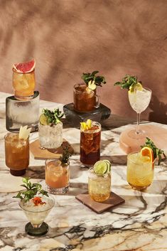 a table topped with glasses filled with different types of drinks and garnishes