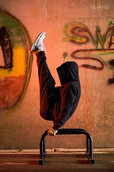 a man doing a handstand in front of a wall with graffiti on it