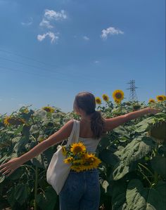 a woman standing in a sunflower field with her arms spread out to the side