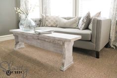 a living room with a couch, coffee table and window in the corner on carpeted flooring