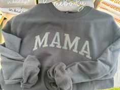 a gray sweatshirt with the word mamma on it sitting in front of other items