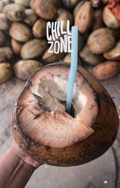 a person holding a coconut drink with a straw in it's mouth and the word chill zone written on top