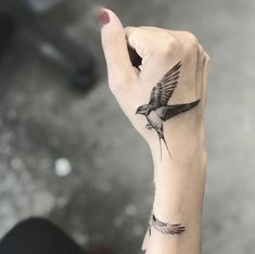 a small bird tattoo on the left wrist and right hand is shown in black ink