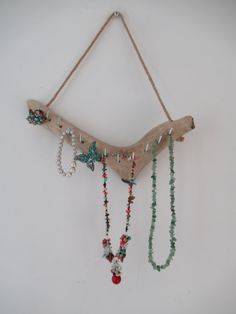 a piece of driftwood with beads hanging from it's sides on a white wall