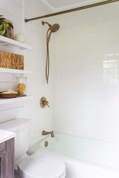 a white toilet sitting next to a bath tub under a shower faucet in a bathroom