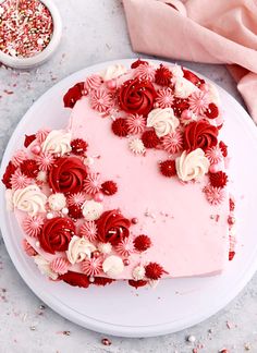 a heart shaped cake on a white plate with red and white flowers in the middle