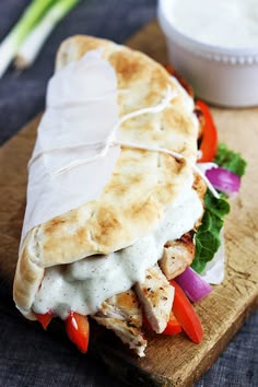 a pita sandwich on a cutting board with vegetables