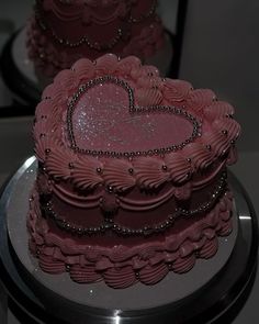 a heart shaped pink cake sitting on top of a table