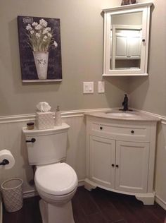 a white toilet sitting in a bathroom next to a sink and mirror on the wall