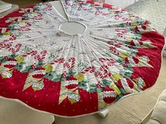 a red and white quilted table top with christmas decorations on it, sitting on a couch